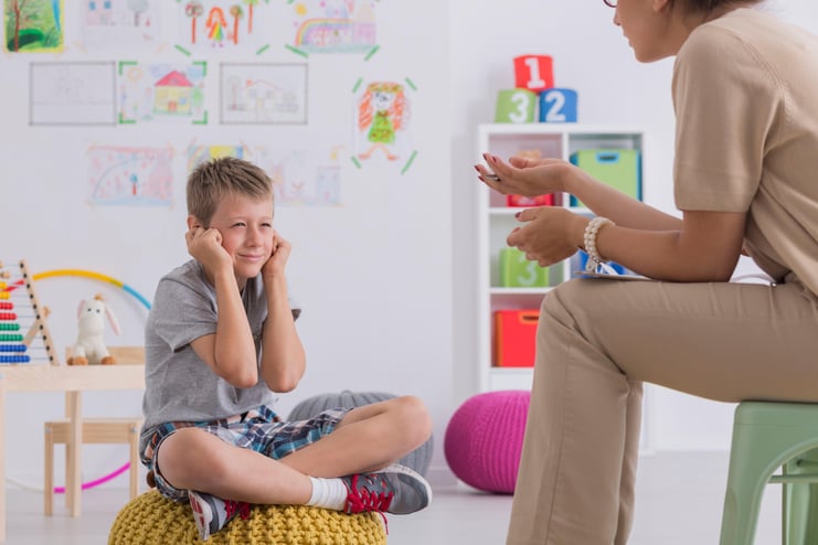 misbehaving-boy-sitting-pouf-session-with-psychotherapist